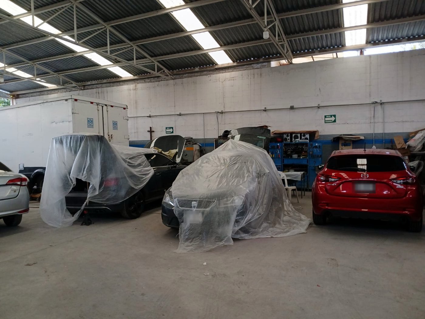Autos cubiertos con plástico protector dentro de la nave