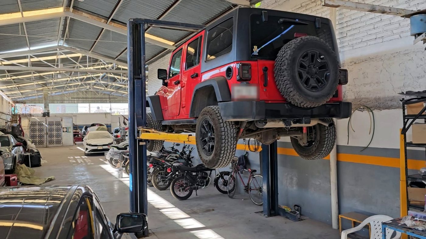 Jeep sobre rampa de elevación tipo portería en la nave